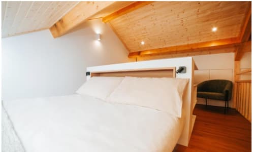 Quarto espaçoso da villa Casa Lobos com vigas de madeira, roupa de cama branca e iluminação aconchegante em Vieira do Minho
