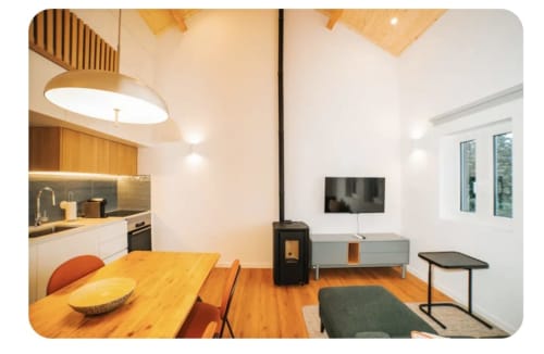 Espaço moderno integrado na villa Casa Lobos em Vieira do Minho com cozinha, mesa de refeições, lareira e zona de televisão