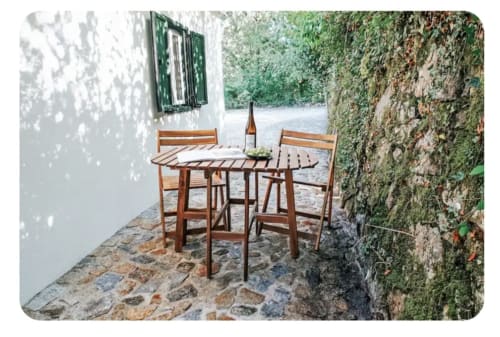 Mesa e cadeiras de madeira na varanda de pedra da villa Casa Colina em Vieira do Minho, Portugal