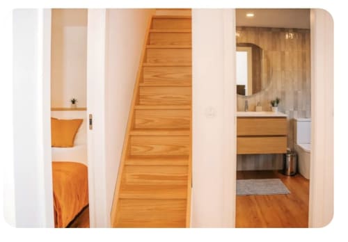 Corredor da villa Casa Colina com escada de madeira, quarto com roupa de cama laranja e banheiro com lavatório e espelho