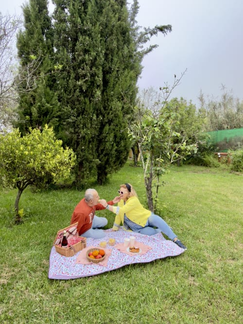 Pareja disfrutando de un picnic sobre manta en el jardín del hotel rural Las Calas, Vega de San Mateo
