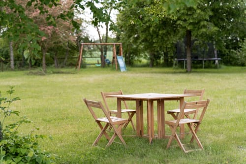 Table et chaises de pique-nique en bois dans le jardin luxuriant de la villa Maisons Noisette, Saint-Pierre-des-Ormes, avec équipements de jeux