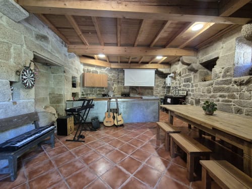 Salón de eventos rústico de piedra con techo de madera, piano, guitarras y comedor en Aldea Rural Pazos De Arenteiro
