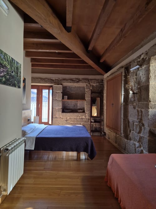 Habitación rústica de piedra con vigas de madera en el hotel rural Aldea Pazos De Arenteiro en España