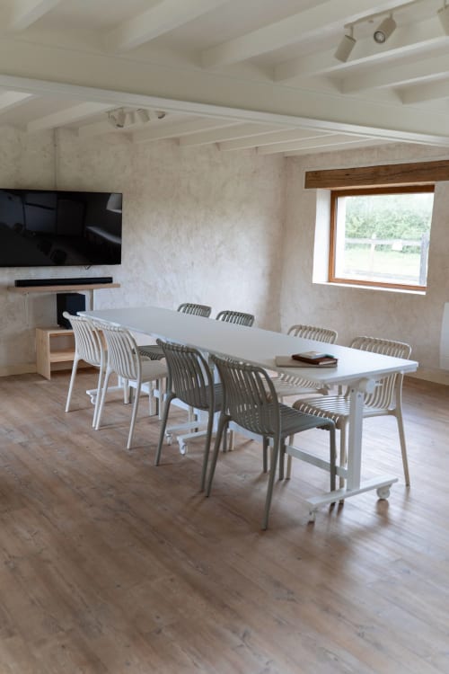 Salle à manger moderne aux Maisons Noisette avec grande table blanche, chaises rayées et poutres en bois