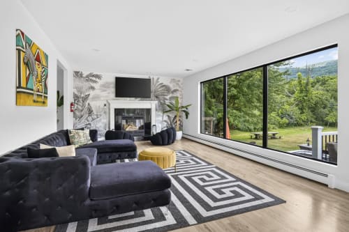 Modern villa living room at Malkita Aria in Woodbury with mountain views, black furniture, fireplace, and large windows