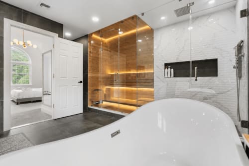 Luxurious spa-style bathroom in Malkita Aria villa with soaking tub, wooden sauna, rainfall shower, marble finishes, and