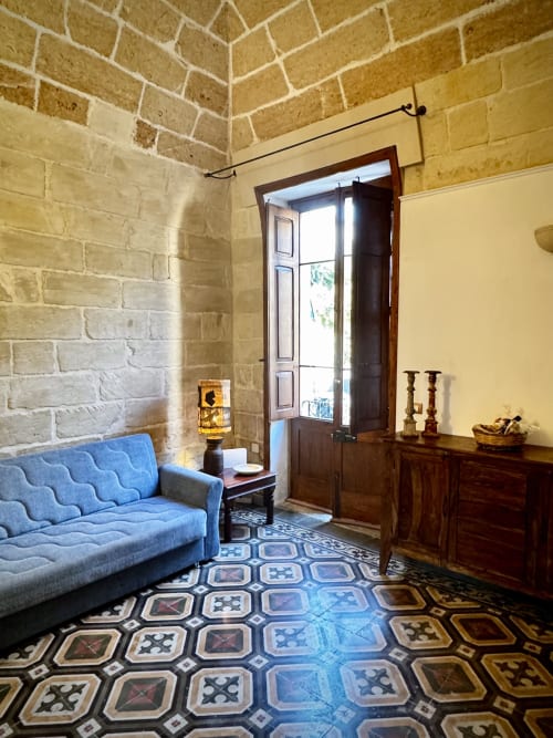 Elegante divano blu nel salotto della dimora in pietra di HABITARE Lecce, con pavimento a piastrelle decorate e arredamento in legno