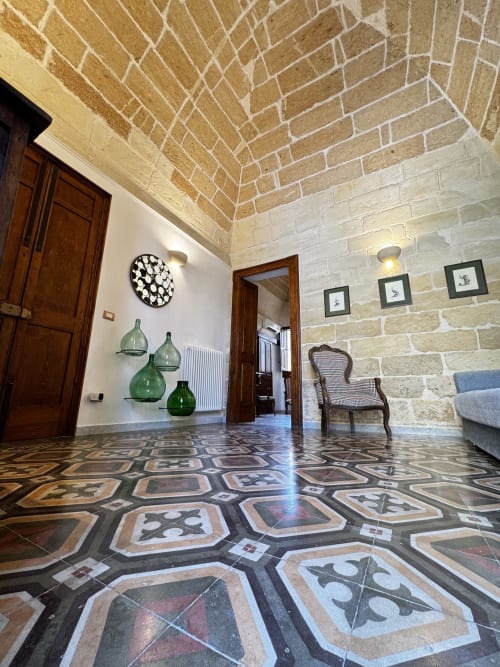 Ingresso di spaziosa dimora leccese con volta in laterizio, pavimento a motivi floreali, porte in legno e decorativi vetri verdi