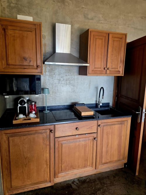 Cozinha moderna na Les Terrasses Les Suites em Calheta com armários de madeira, bancadas pretas e coifa de aço inoxidável