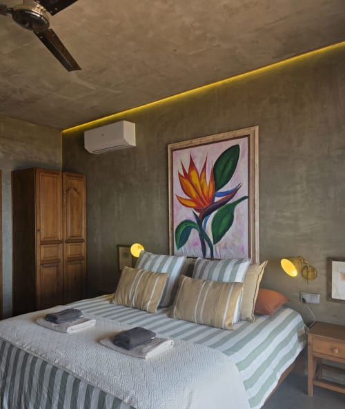 Suite moderna em Les Terrasses Les Suites Calheta com roupa de cama listrada, arte com aves tropicais e iluminação ambiente