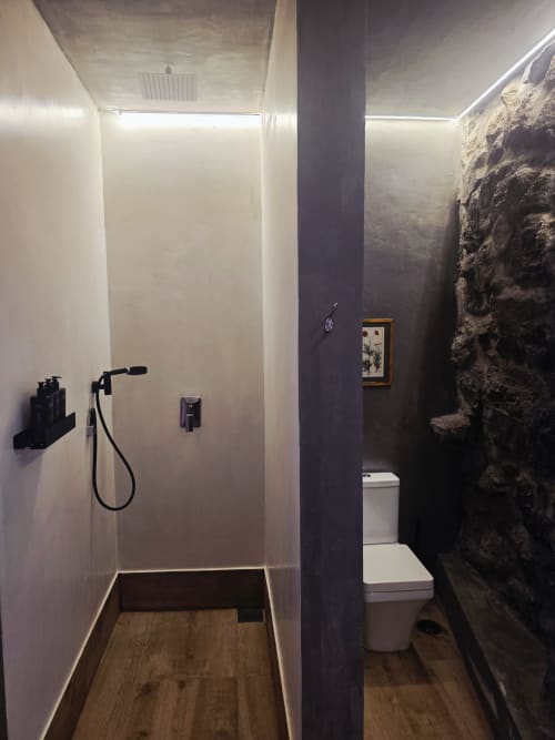 Banheiro moderno no hotel Les Terrasses Les Suites em Calheta com chuveiro aberto, parede de pedra e design contemporâneo