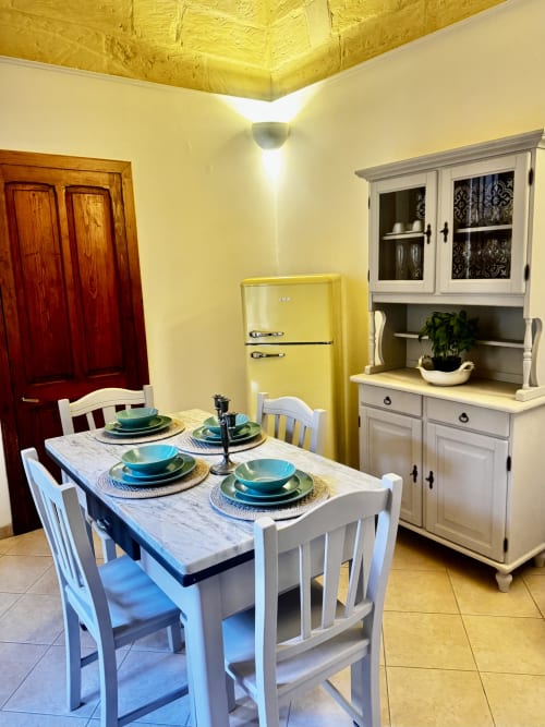 Zona pranzo retrò all'HABITARE Lecce con soffitto giallo, frigorifero vintage e tavolo apparecchiato per quattro