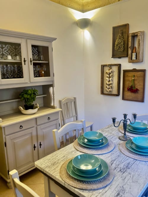 Elegante sala da pranzo dell'appartamento HABITARE Lecce con segnaposto turchesi, tavolo in marmo e arredamento bianco.