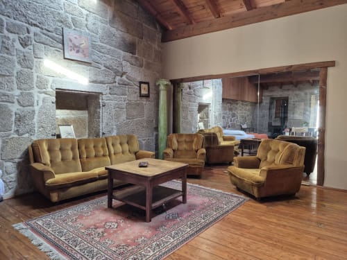 Spacious living room at Aldea Rural Pazos De Arenteiro with stone walls, golden upholstered furniture, wooden beams, and