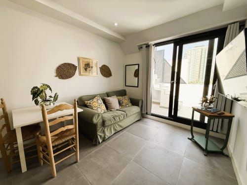 Moderno salón en apartamento de lujo frente al mar en Fuengirola con sofá, mesa de comedor, sillas de madera y terraza con vistas al mar