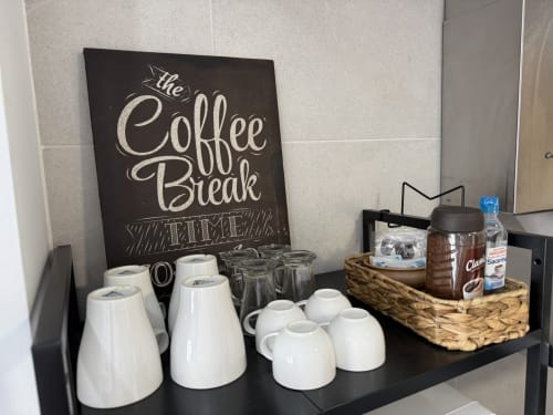 Zona de café en apartamento de lujo junto a la playa en Fuengirola con tazas, hervidor y letrero decorativo