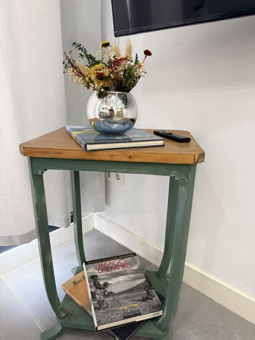Mesa auxiliar de madera verde con arreglo de flores secas en jarrón plateado y libros en elegante apartamento de Fuengirola