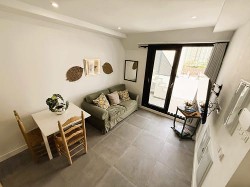 Moderno salón de apartamento frente al mar en Fuengirola con sofá gris, comedor, acceso a terraza y decoración contemporánea