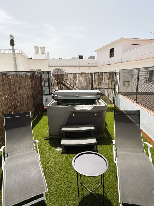 Terraza de lujo en azotea de Fuengirola con jacuzzi, tumbonas, zona de comedor y césped sintético