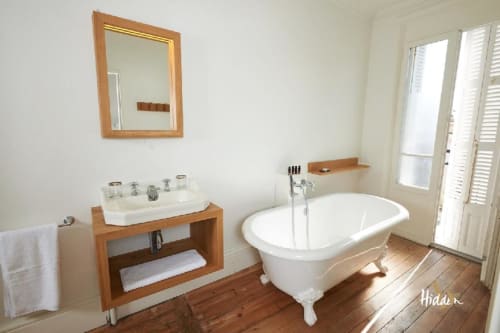 Elegant bathroom in Suite Juliette at Hidden Bay Hotel, Cayeux-sur-Mer, featuring white clawfoot tub, wooden vanity sink, and