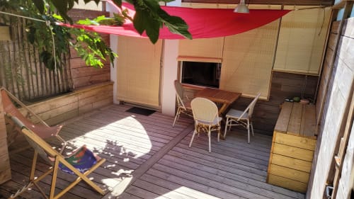 Terrazza privata del Le Lodge du Cap Ferret con ponte in legno, tenda rosa, scrivania, sedie e verde del giardino