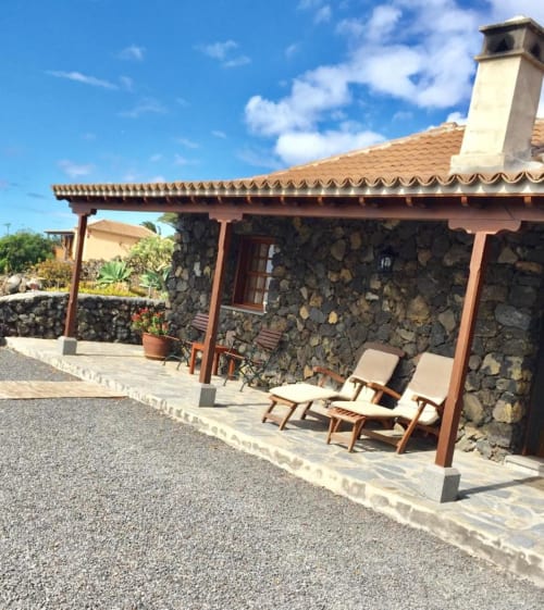 Patio de casita de piedra con tumbonas y pérgola de madera, hotel La Palma entre viñas y Teneguía