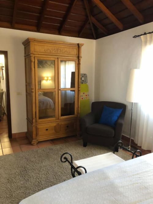 Dormitorio espacioso con armario de madera, sillón negro y luz natural en villa Los Llanos Negros Country House