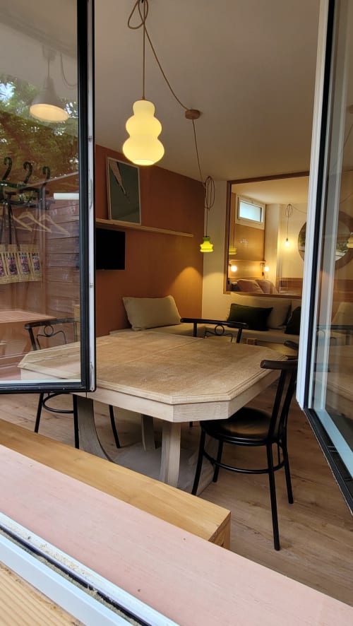 Zona pranzo del Tiny Lodge a Le Lodge du Cap Ferret con lampade a sospensione gialle e accesso alla terrazza