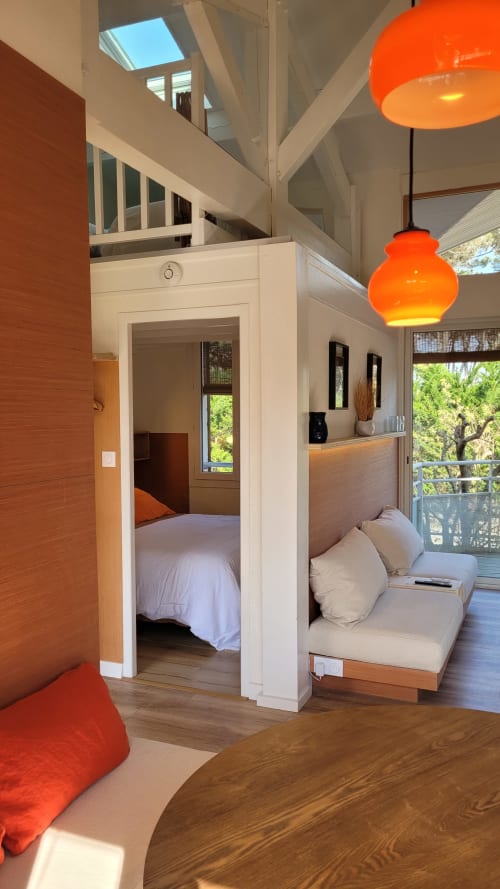 Modernes Studio im Lodge du Cap Ferret mit Schlafzimmer, Wohnbereich, orangenen Pendelleuchten und Gartenblick