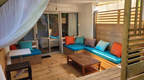 Terrazza luminosa con sedute imbottite blu, ponte in legno e vista sul giardino al Lodge du Cap Ferret