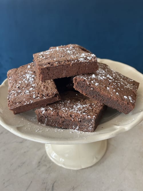 Carrés de brownie au chocolat en poudre présentés sur un piédestal crème à l'Hôtel Hidden Bay, Cayeux-sur-Mer