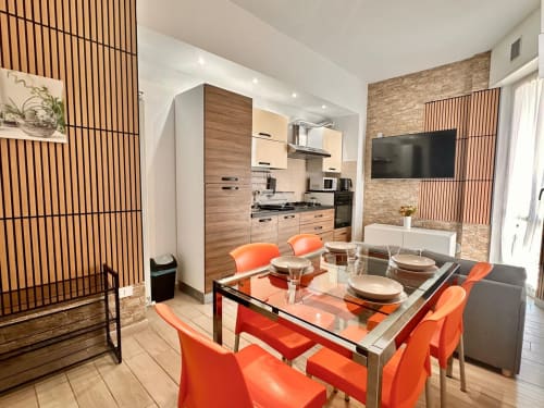 Zona pranzo moderna con sedie arancioni e cucina, Loano Italia