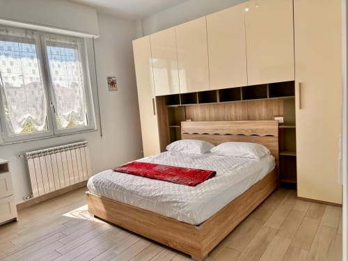 Camera da letto moderna con letto in legno, armadio color crema e vista giardino dell'Oasi del mar a Loano, Italia