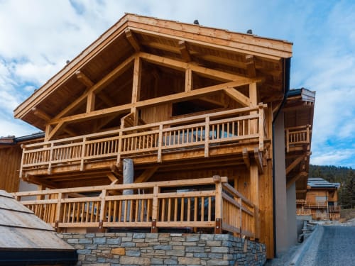 Chalet de luxe en bois avec plusieurs balcons aux Tanières de Montgenèvre, vue sur les montagnes, soubassement en pierre, près des pistes