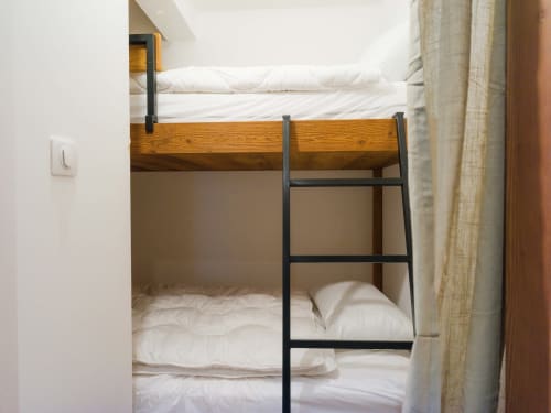 Lit superposé avec cadre en bois et échelle en métal noir dans la chambre de l'appartement de Montgenevre