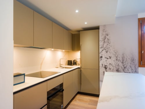 Cuisine moderne aménagée avec mobilier sauge, plan de travail blanc et papier peint montagne enneigée, Sage des Montagnes