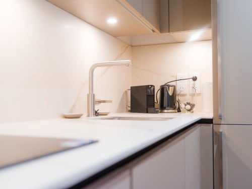 Cuisine moderne avec comptoir blanc, évier, robinetterie et cafetière dans l'appartement Les Tanières de Montgenèvre
