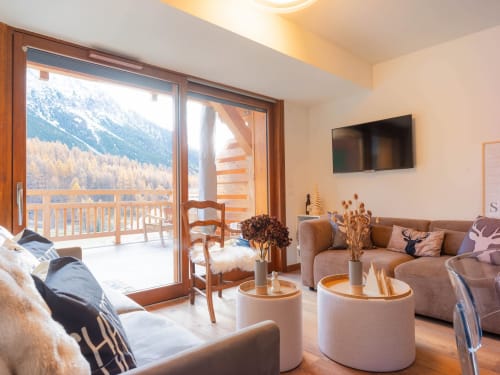Salon d'appartement alpin luxueux avec vue sur les montagnes, mobilier moderne et terrasse panoramique dominant Montgenèvre