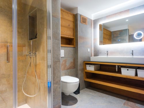 Salle de bain moderne avec douche à l'italienne, double vasque avec étagères en bois, miroir chauffant et sol chauffant