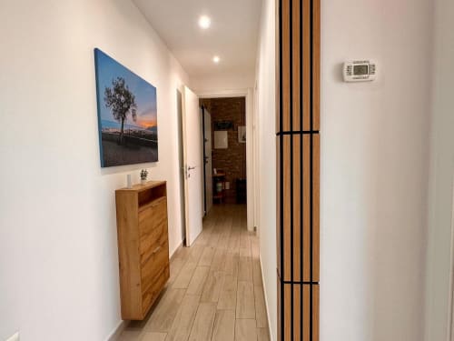 Moderno corridoio nell'appartamento di Loano con arredamento in legno, quadri al tramonto e illuminazione incassata
