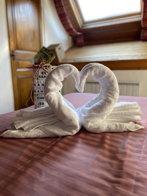 Two white towel swans forming a heart on a bed in Chambre Maupassant at La Jument Verte, Trévignin
