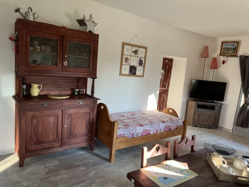 Rustic bedroom at LA JUMENT VERTE cottage with wooden bed, antique furniture, TV, and traditional decor