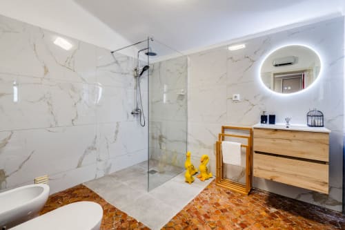 Modern bathroom at Quinta do Águas villa in Lagoa with marble tiles, glass shower, wooden vanity, and heated mirror.