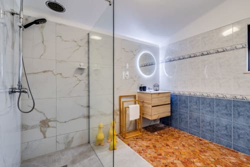 Modern bathroom at Quinta do Águas villa in Lagoa with marble tiles, rainfall showerhead, wooden vanity, and terracotta
