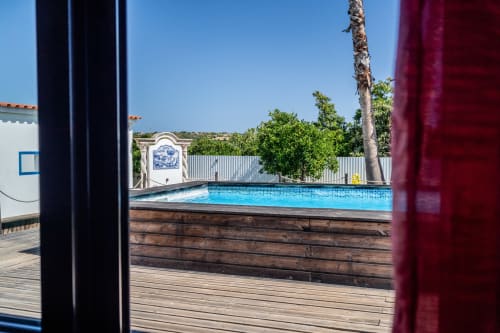 Private pool and wooden deck at Quinta do Águas villa in Lagoa, Portugal with palm tree and garden view