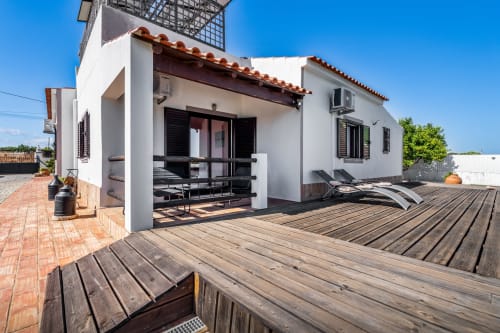 Modern white villa in Lagoa with wooden terrace, lounge seating, and BBQ area under blue sky