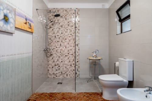 Modern bathroom with walk-in shower, mosaic tiles, toilet, sink, and decorative elements at Quinta do Águas villa in Lagoa,
