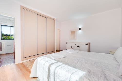 Bright bedroom with built-in wardrobe, white bedding, and wooden flooring in Quinta do Águas villa, Lagoa, Portugal