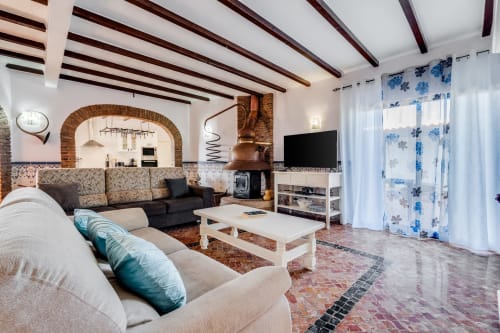 Spacious living room in Quinta do Águas villa, Lagoa, with exposed beams, fireplace, comfortable seating, and pool view
